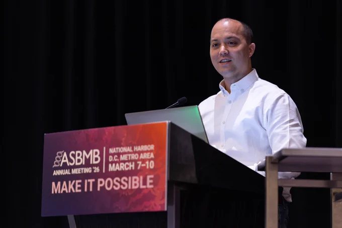 James Olzmann stands at a podium with a laptop delivering a talk at the 2026 ASBMB Annual Meeting.