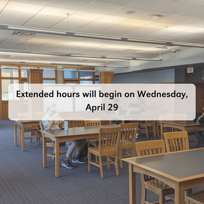 A library with wooden tables and chairs, there are students sitting at the chairs. Over the top of the photo, the text says 'extended hours will begin on Wednesday, April 29'