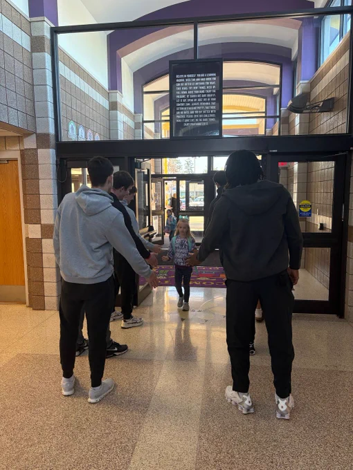 A female student getting greeted with high fives from the ISU football team.