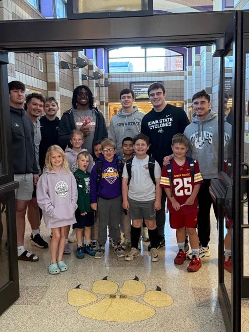 A group of Iowa State football players standing behind a group of Central Elementary Students