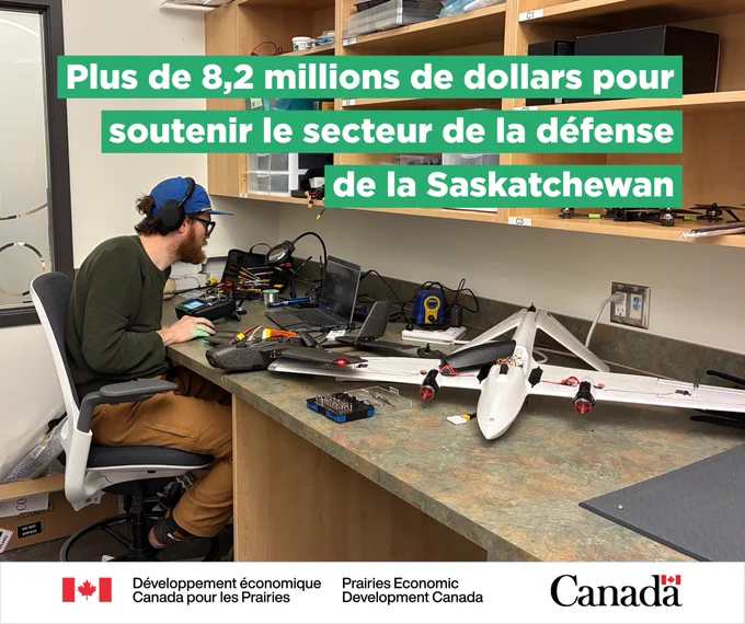 Un étudiant adjoint de recherche à la Sask Polytech travaille à un bureau muni d’un gros drone, avec le texte : « Plus de 8,2 millions de dollars pour soutenir le secteur de la défense de la Saskatchewan ».