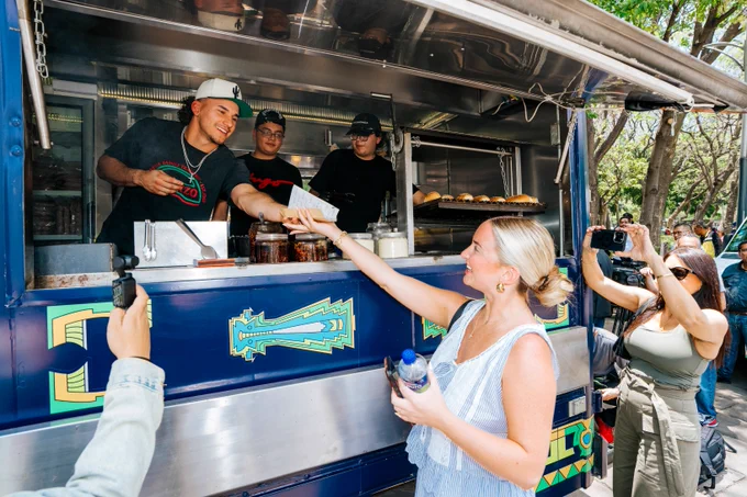 Alek Thomas serves his wife a hot dog from a food truck. 