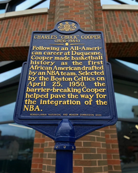 Pennsylvania Historical and Museum Commission sign outside of the UPMC Cooper Fieldhouse. It reads: Charles "Chuck" Cooper, 1926-1984. Following an All-American career at Duquesne, Cooper made basketball history as the first African American drafted by an NBA team. Selected by the Boston Celtics on April 25, 1950, the barrier-breaking Cooper helped pave the way for the integration of the NBA.
