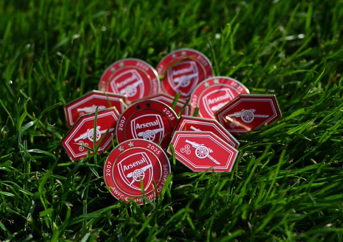 A cluster of programme pin badges on the Emrates Stadium turf