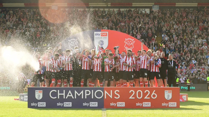 Lincoln City players and staff behind a champions 2026 banner.