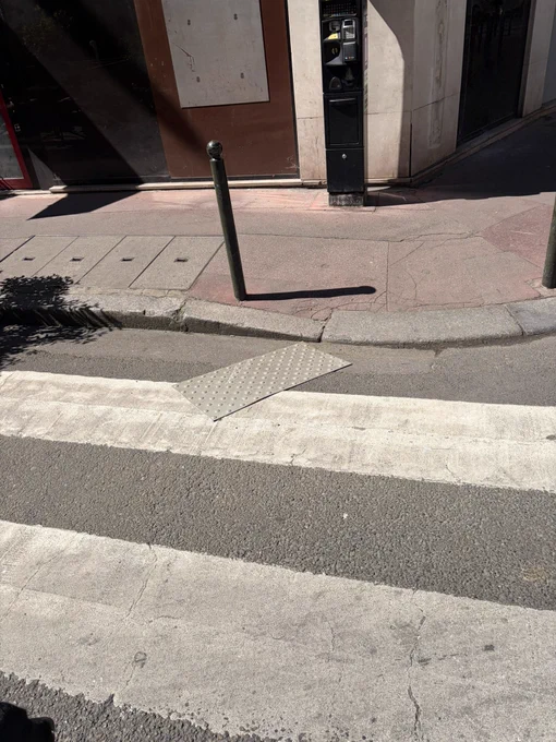 Passage piéton sur lequel on remarque une bande photo tactile décollé et sur la bordure du trottoir rien du tout comme si que rien avait été posé