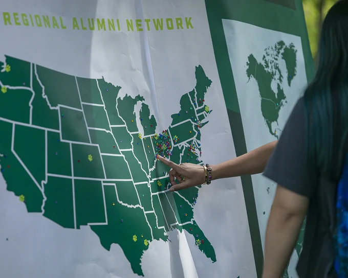 People putting a pin into a regional alumni network map