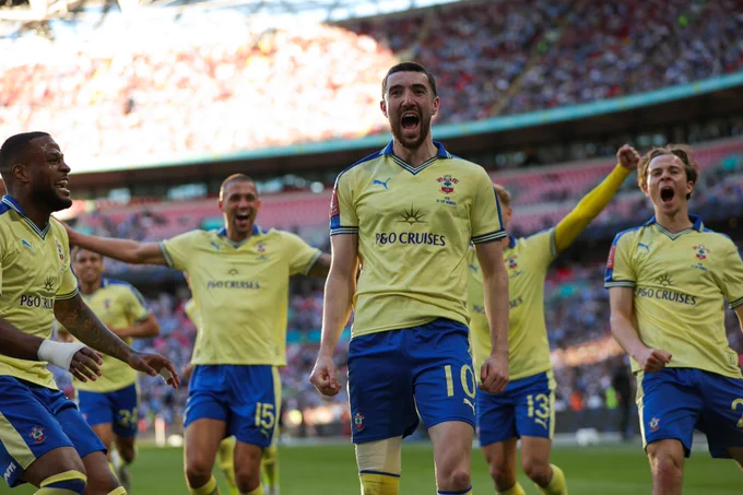 Finn Azaz, centre, celebrates his goal against Manchester City, wearing the 76 yellow and blue shirt and blue shorts with yellow socks. From left to right behind him is Cyle Larin, Shea Charles, Nathan Wood, Leo Scienza and Caspar Jander.