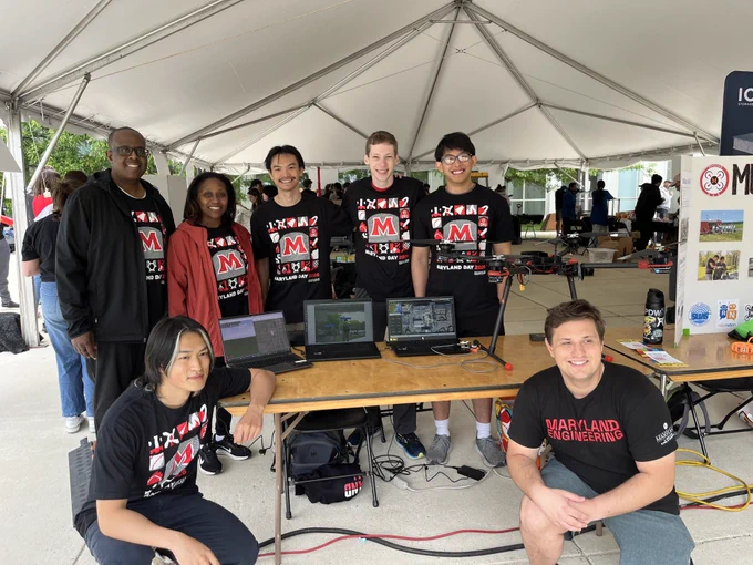 Dean Graham poses with students who stand around a table with three laptops