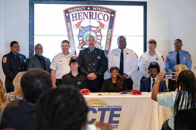 Henrico Schools students sit and pose for a photo with Henrico Fire representatives after signing on CTE Signing Day.