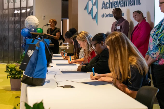 Students sit down to sign contracts for future employment with Henrico County Public Schools at CTE Signing Day.