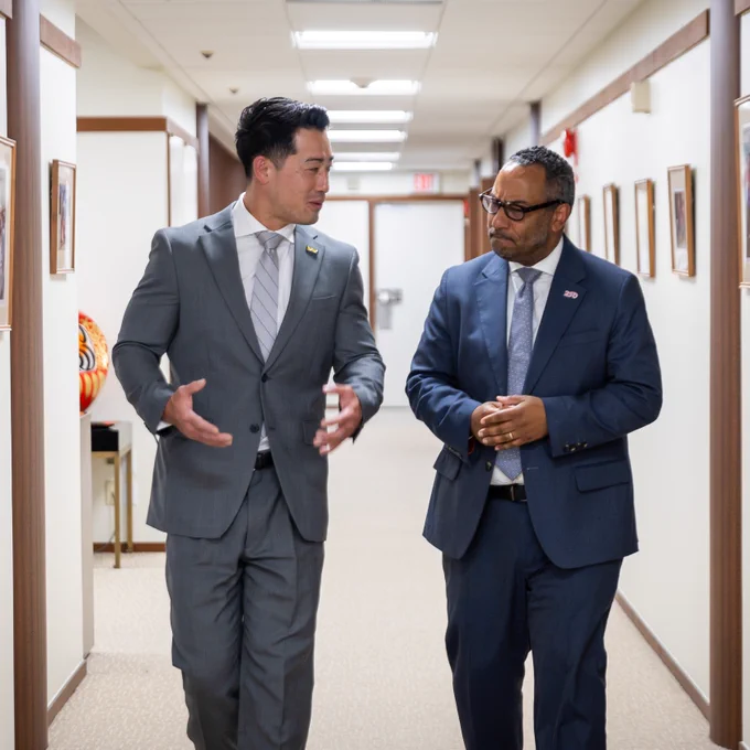 Two men walking down a hallway and talking. 
