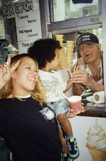 Mom holding young son who is high-fiving Ray of Ray’s Candy Store in New York City.