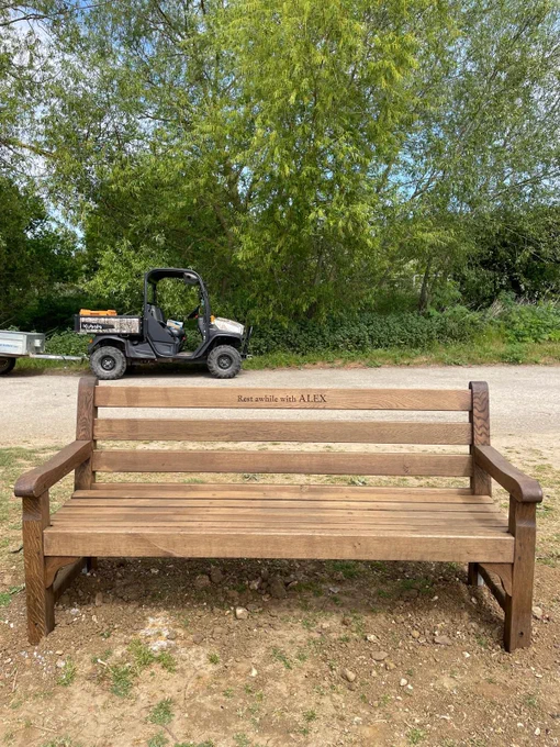 A wooden bench inscribed with Rest awhile with Alex