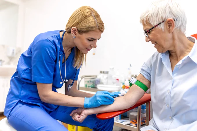 A phlebotomist draws a woman's blood.