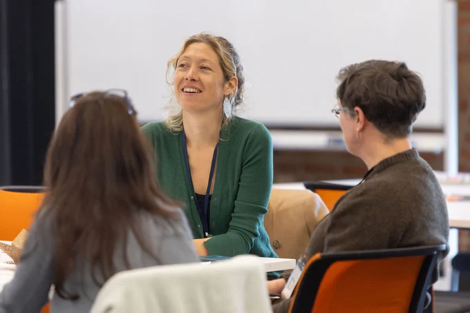 Three people conversing at a conference table