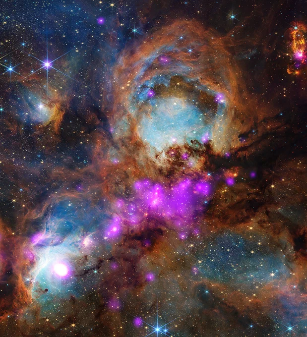A colorful section of the Cat\u2019s Paw Nebula. Four circular areas are shown in the center of the image, each glowing blue. Rusty wisps of dust are interspersed amongst them. Luminous blotches of purple decorate the dust, as well as diffuse yellow and blue stars. Credit: X-ray: NASA/SAO/CXC; Infrared: NASA/ESA/CSA/STScI; Image Processing: NASA/CXC/SAO/J. Major
