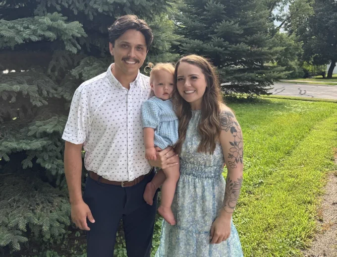 Sydni Smith smiling at the camera with her husband and daughter