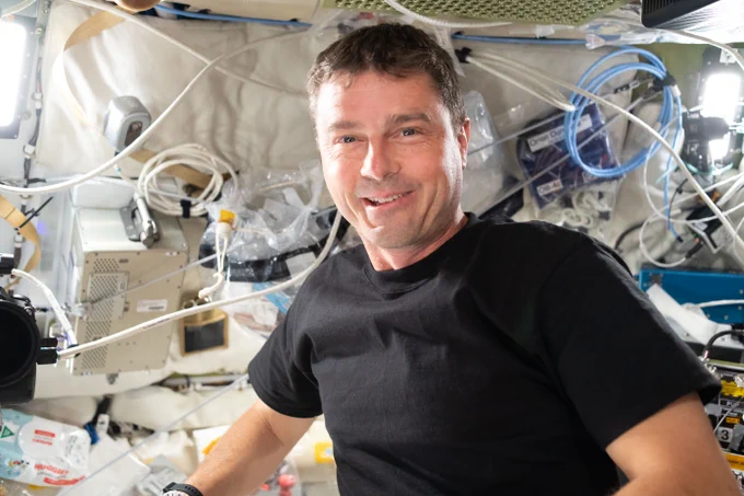 Reid Wiseman smiles at the camera inside of the spacecraft. He is wearing a black T-shirt. Credit: NASA