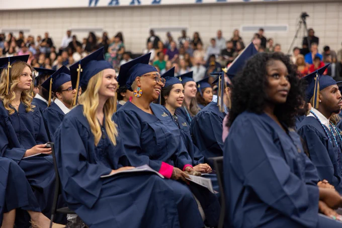 Graduates smile during commencement.
