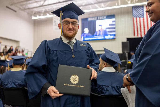 Geoffrey Davis smiles with diploma in hand.