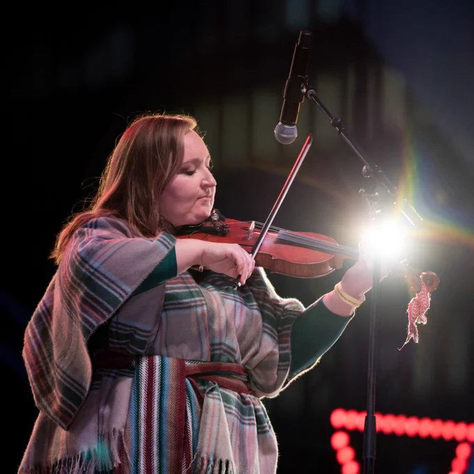 Musician playing violin on stage.