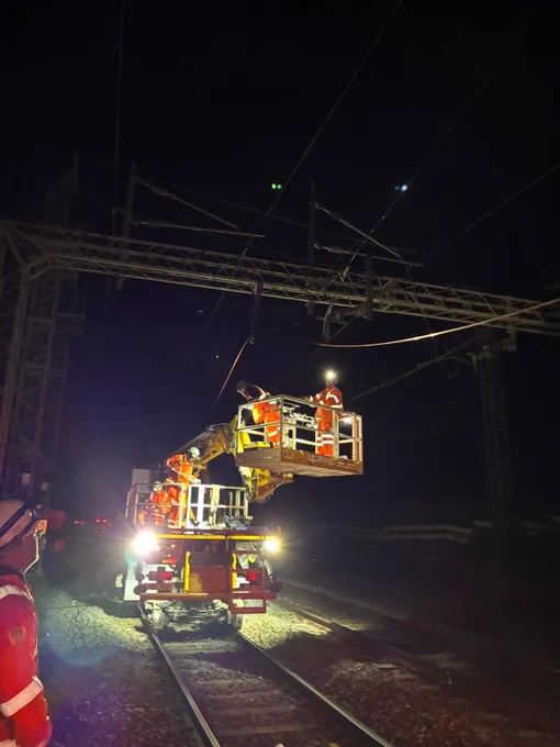 A photo of overnight work taking place in Bourne End near Berkhamsted where Network Rail engineers are working to repair damaged overhead line equipment on the West Coast Main Line. In the photo you can see rail engineers working on a special track mounted machine to replace wires that provide power to electric trains.
