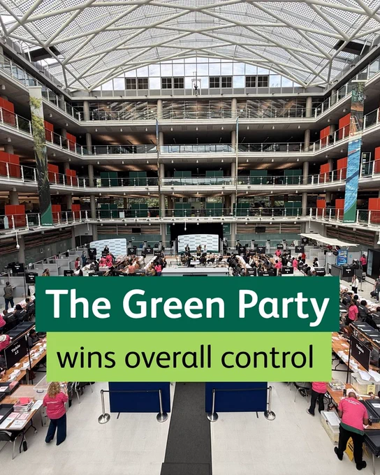 The Green Party wins overall control. Image shows a large atrium with people and tables, overlaid with text.