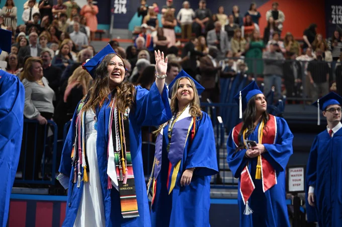 Graduates waving to loved ones.