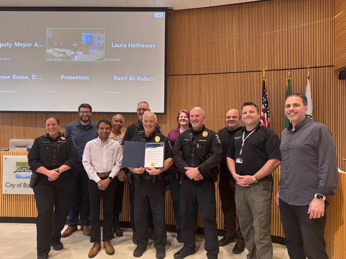 Various members of the Bothell Police Department stand with Bothell City councilmembers in Council Chambers inside Bothell City Hall. One of the officers is holding a proclamation. 