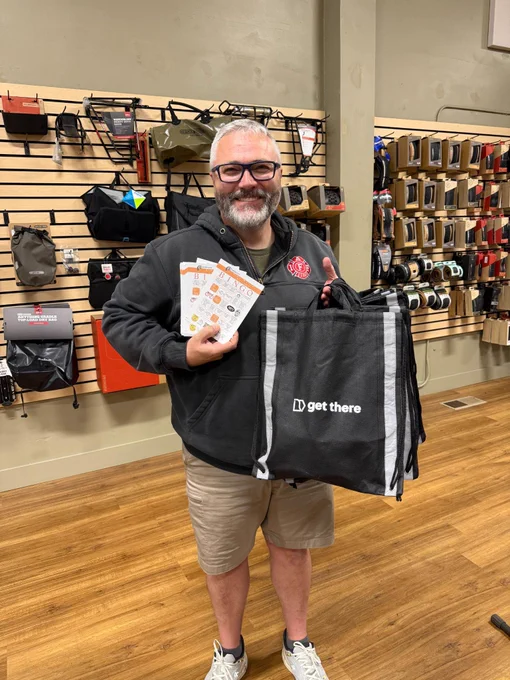 Image of a guy holding bike bingo cards and a GetThere bag