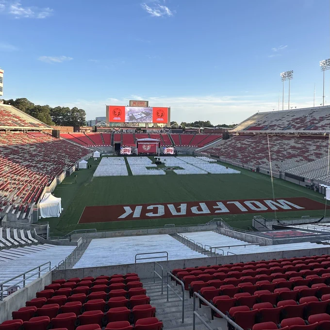 An empty Carter-Finley Stadium with lines of white chairs and a stage on the field.