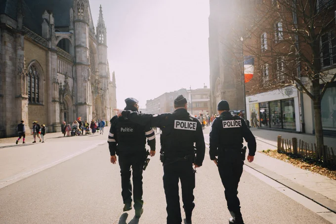 Photographie de deux policiers Français et d’un policier néerlandais lors du carnaval de Dunkerque de 2025. On les voit marcher de dos dans la même direction.