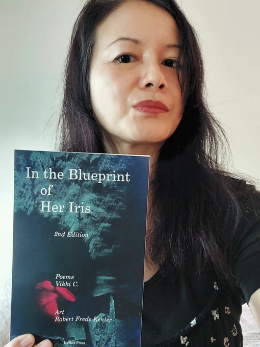 Vikki C. holding a copy of In the Blueprint of Her Iris (2nd edition - 2026), published by Ice Floe Press.