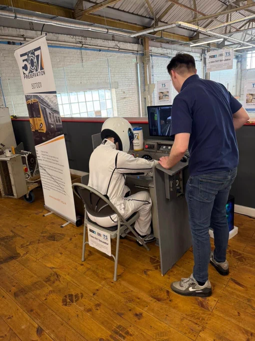 A man dressed in a Stig-like outfit at the control of the 507 sim