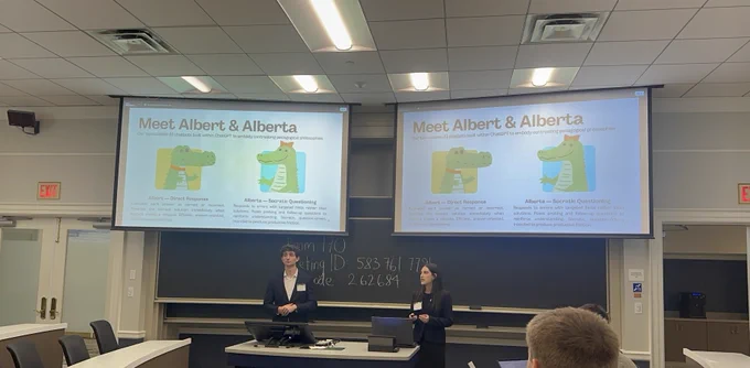 Two University of Florida student researchers present their award-winning AI and engineering education research in a classroom conference setting. A presentation slide titled “Meet Albert & Alberta” is projected on large screens behind them, explaining two AI chatbot approaches for engineering problem solving.