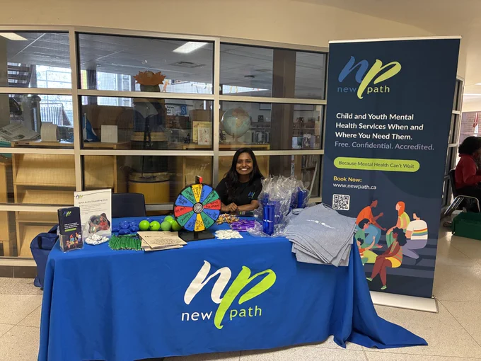 New Path mental health services booth with informational materials, stress balls, and a prize wheel at a community event.