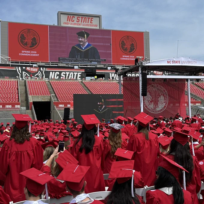 CALS Dean Garey Fox speaking at Spring Commencement at Carter-Finley Stadium to a crowd of NC State graduates in red caps and gowns.