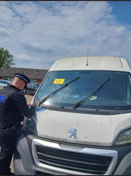 Officer with seized van applying 'untaxed vehicle' sticker to the windscreen