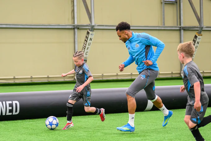 Under-8s players playing football with Jacob Murphy. 