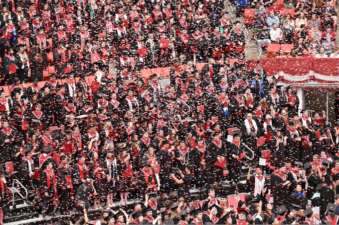 Color indoor photo of confetti falling from the ceiling in Beasley Coliseum with graduates looking on. 
