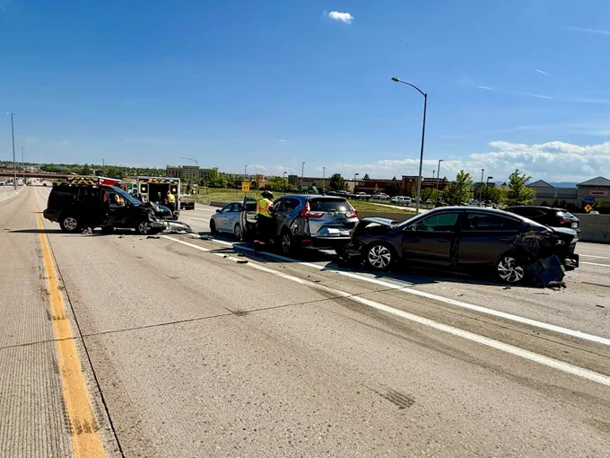 Daytime image of a multiple vehicle accident on a highway with firefighters and ambulances