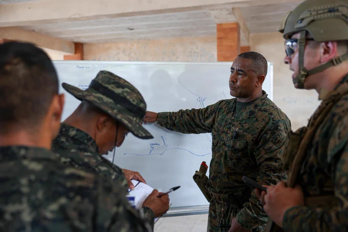 U.S. Marine Corps Gunnery Sgt. Patrick Auten, a reconnaissance Marine with 4th Reconnaissance Battalion, reviews the plan for a personnel recovery training scenario with Salvadoran marines with the 1st Marine Brigade of El Salvador during CENTAM Guardian 2026 in La Union, El Salvador, April 22, 2026. CG 26, an annual, multinational exercise, brings together military and security personnel from El Salvador, Honduras, Guatemala, Costa Rica, Belize, the Dominican Republic, and the United States, ensuring seamless interoperability in times of crisis and contingency response while also demonstrating a united front against shared regional security challenges. (U.S. Marine Corps photo by Sgt. Samuel Qin)