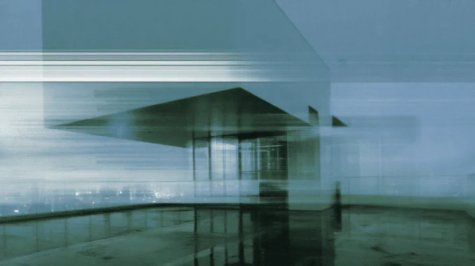 Blurred rooftop structure emerging through rain, reflection, and blue-green atmospheric haze at night in Tokyo