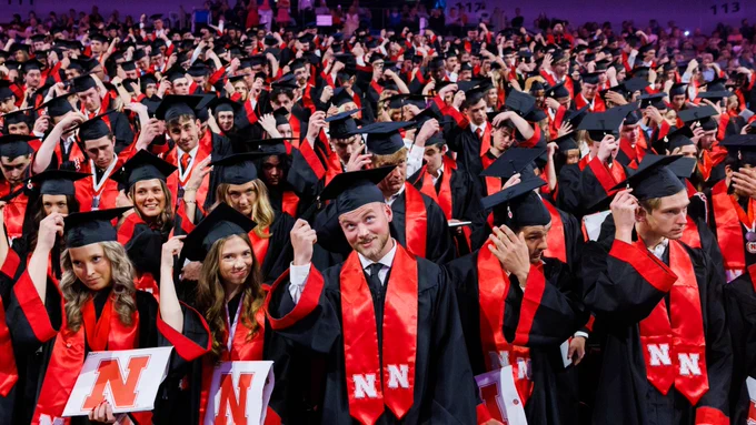 Dozens of Husker graduates, wearing black robes with red stoles, turn the tassels on their mortarboards. (Jordan Opp/University Communication and Marketing)