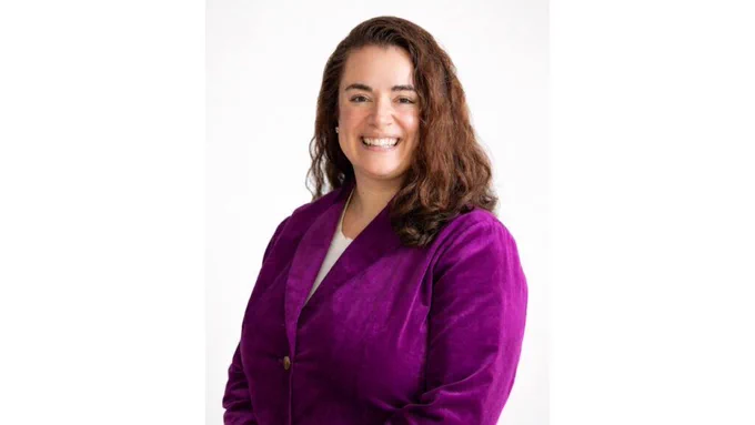 A woman with brown hair and a purple blazer.