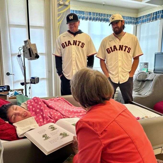 Webb and Walker smiling while reading a book to a child