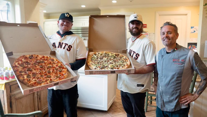 Webb and Walker posing for a photo with their pizzas