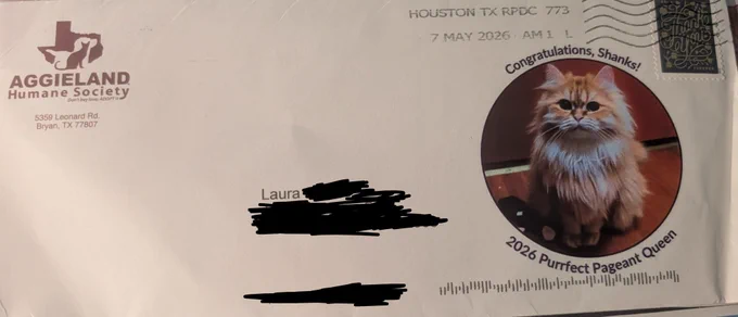 An envelope from the Aggieland Humane Society has a round photo of Shanks the ginger Persian mix with the text, "Congratulations, Shanks! 2026 Purrfect Pageant Queen"