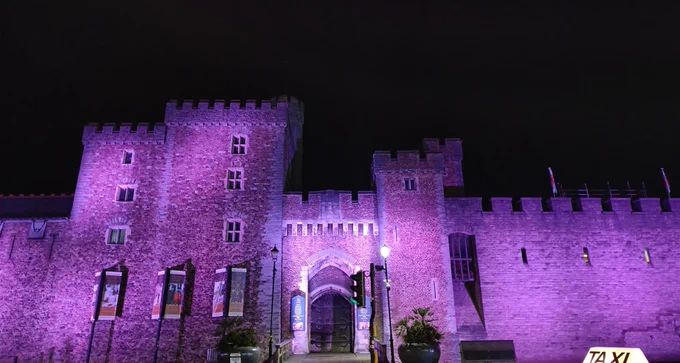 Cardiff Castle illuminated in purple light at night  Castell Caerdydd wedi'i oleuo mewn golau porffor yn y nos